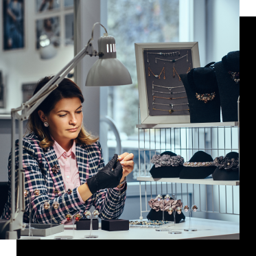 Fotografía de una mujer inspeccionando joyas de plata en un taller